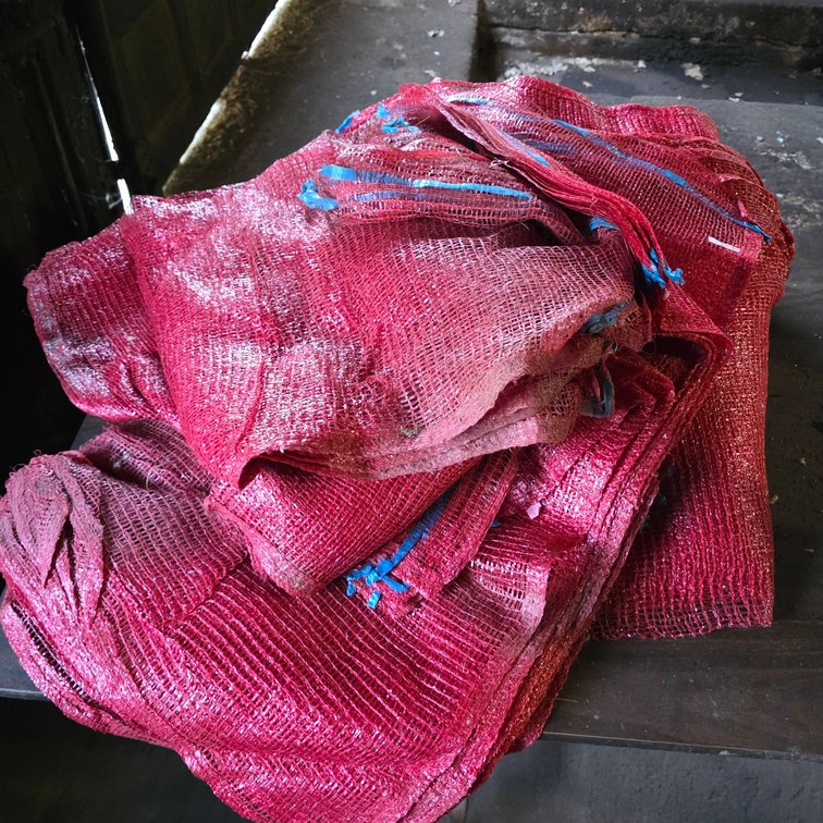 Pile of Red Mesh Plastic Gunny Sacks