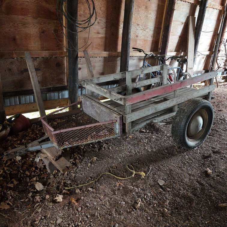 Wooden Farm Utility Trailer with Wire Mesh Front, Steel Wheels, and Red Painted Rail