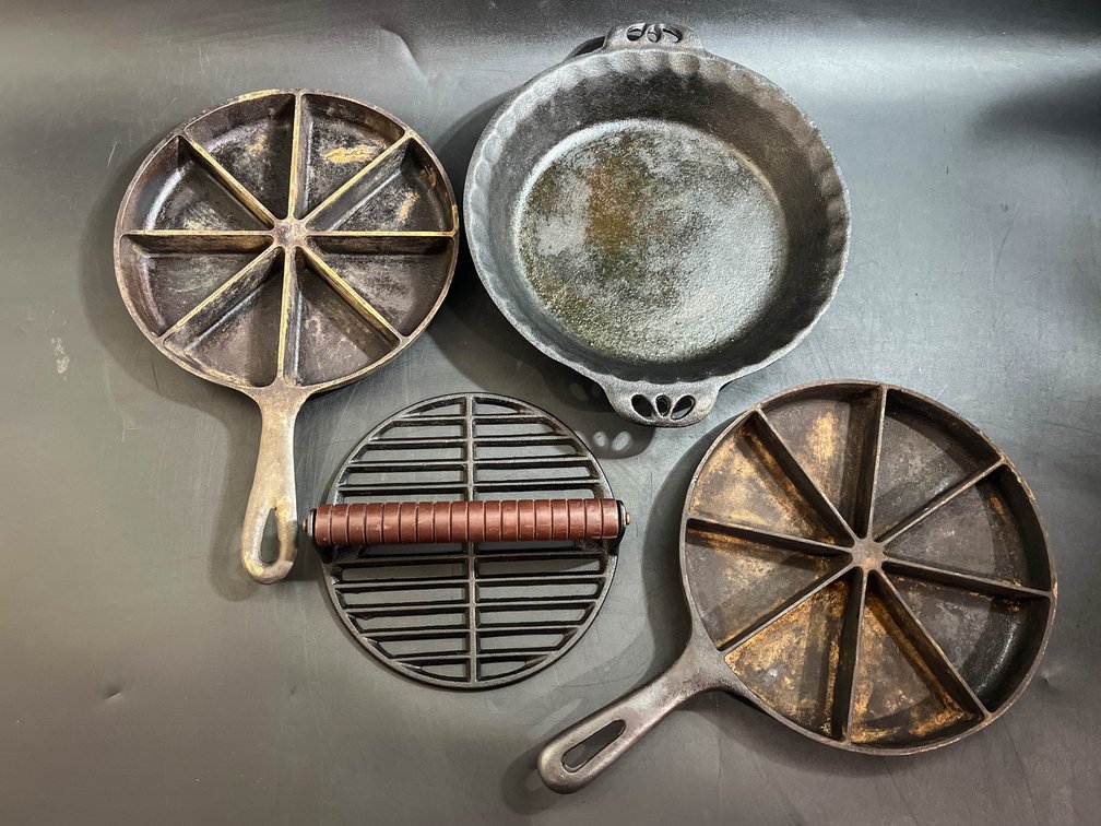 Two cast iron cornbread pans, cast iron steak weight, and cast iron pan