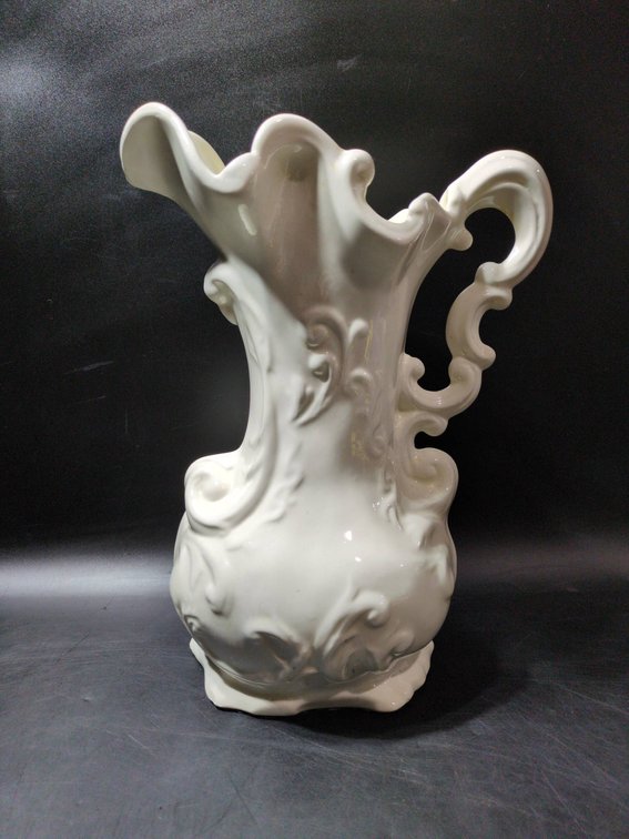 White Ceramic Ornate Pitcher with Scroll Handle and Decorative Relief