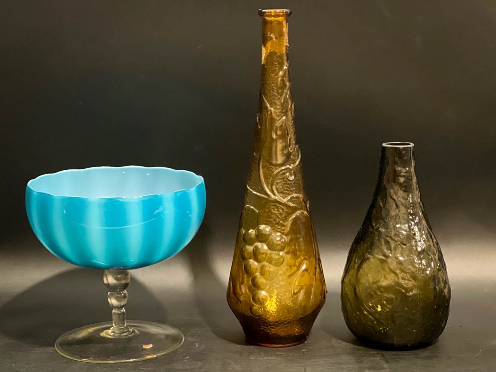 Three Glass Vessels: Blue Pedestal Bowl, Amber Grapevine Bottle, and Brown Textured Vase