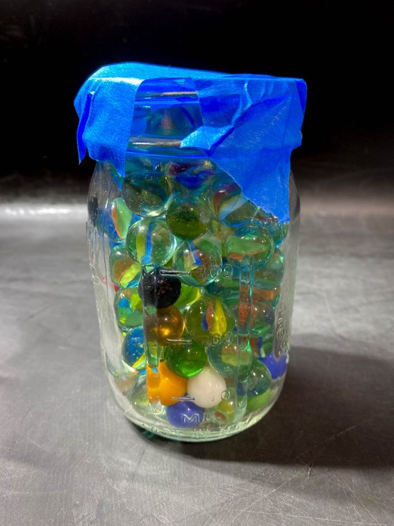 Glass Jar Filled With Assorted Marbles and Blue Tape Lid