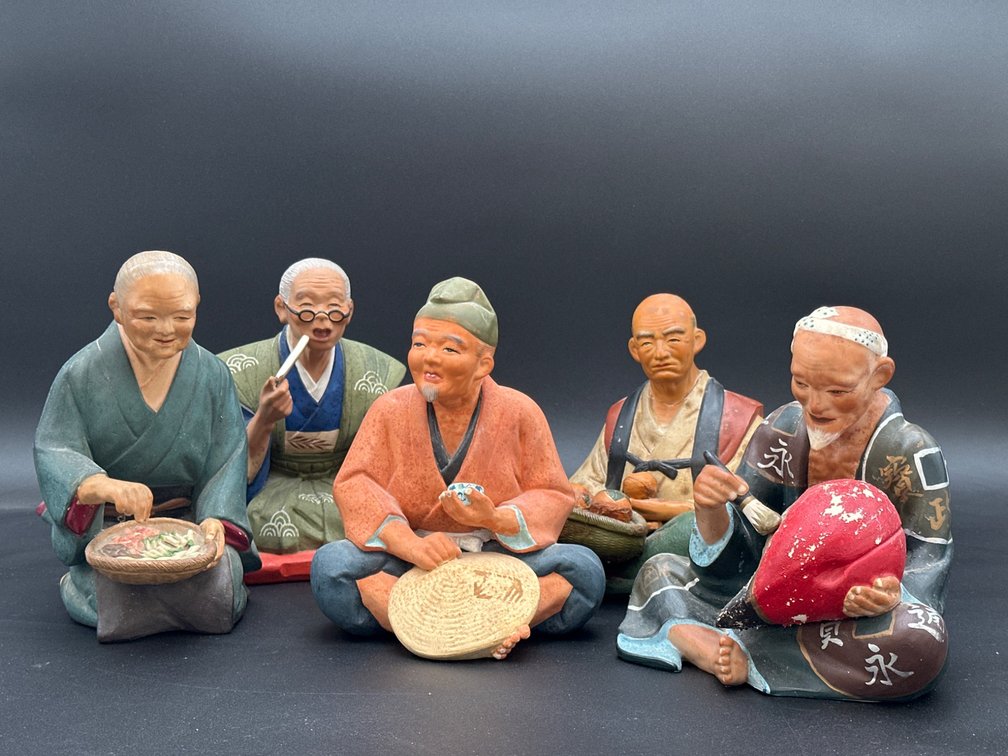 Five Japanese Figurines Depicting Seated Elders Engaging in Traditional Crafts