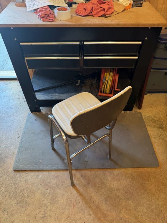 IN BARN IN PAW  PAWS WORKSHOP: Black table, (4) Drawers, Misc Items, In and On It. Items on Wall and Above White Stool and Rubber Mats
