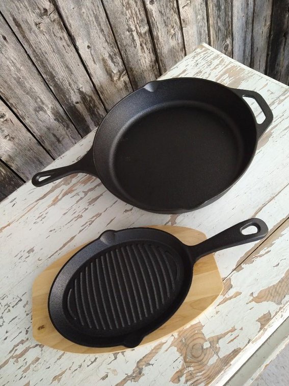 CAST IRON SKILLET SET. LARGE CAST IRON SKILLET, SMALL CAST IRON SKILLET, HANDLE MITT, AND WOOD TRIVE