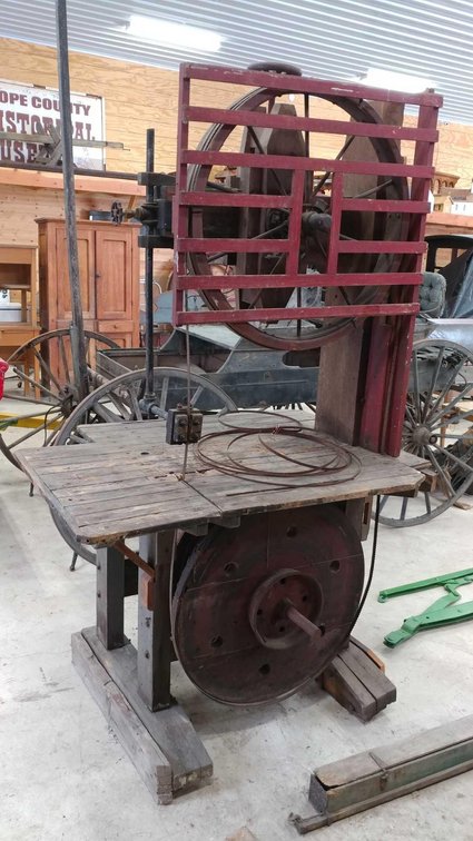 THIS BAND SAW IS 7 FEET HIGH ON A 4 X 3 FOOT BED. THERE IS A LARGE IRON SCREW FOR ADJUSTMENTS. A RED