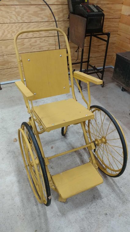 METAL FRAME WHEELCHAIR WITH WOODEN BACK AND SEAT. USED IN THE EARLY GLENWOOD HOSPITAL ON MINNESOTA A