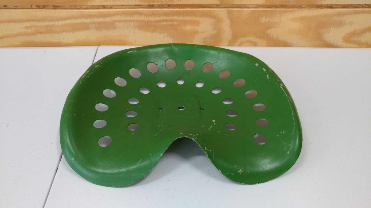 GREEN SEAT FOR A TRACTOR. IT HAS ROUND HOLES.