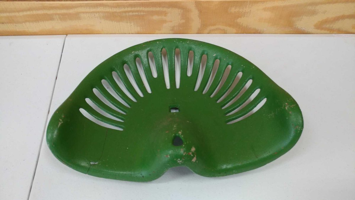 GREEN SEAT FOR A TRACTOR. IT HAS OBLONG HOLES.