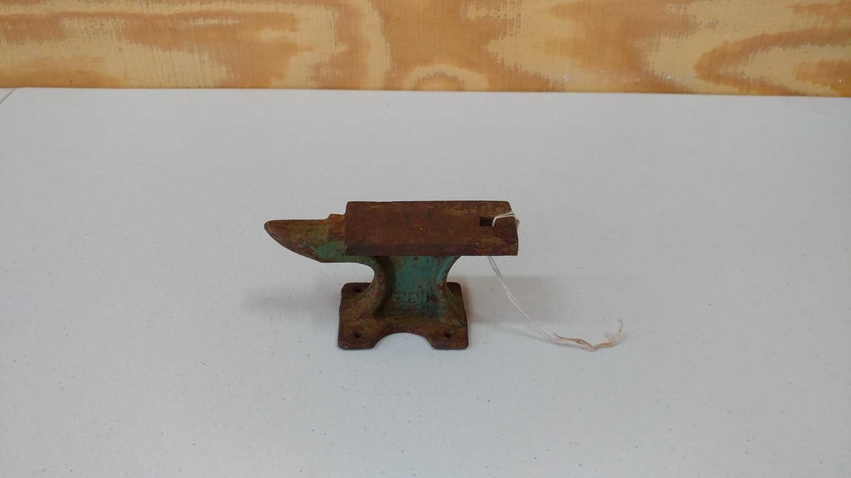 A TINY ANVIL. IT WAS ONCE PAINED A TEAL BLUE. 