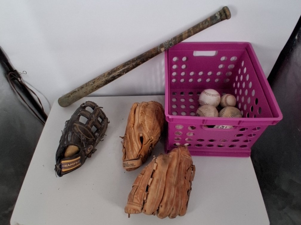 lot of softballs, mits, and a wooden bat