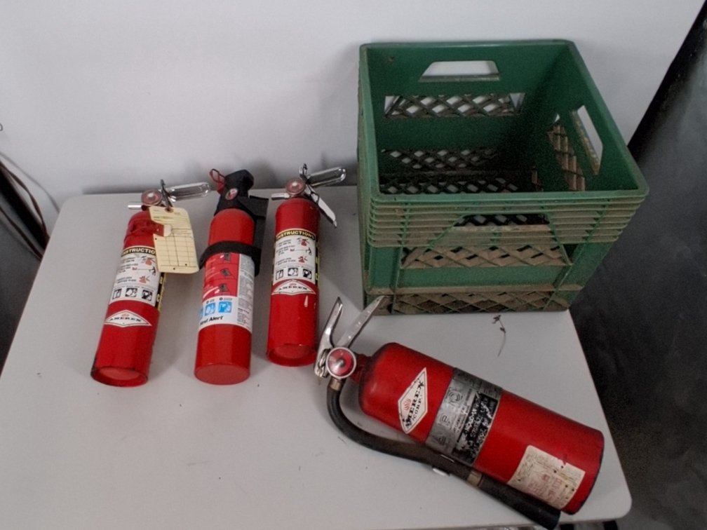 4 fire extinguishers in a plastic milk crate