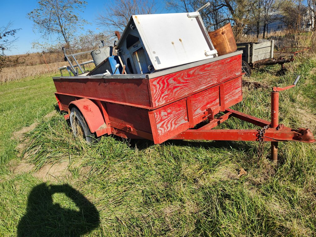 Red Trailer, appears to dump or tilt.  With wood side boards