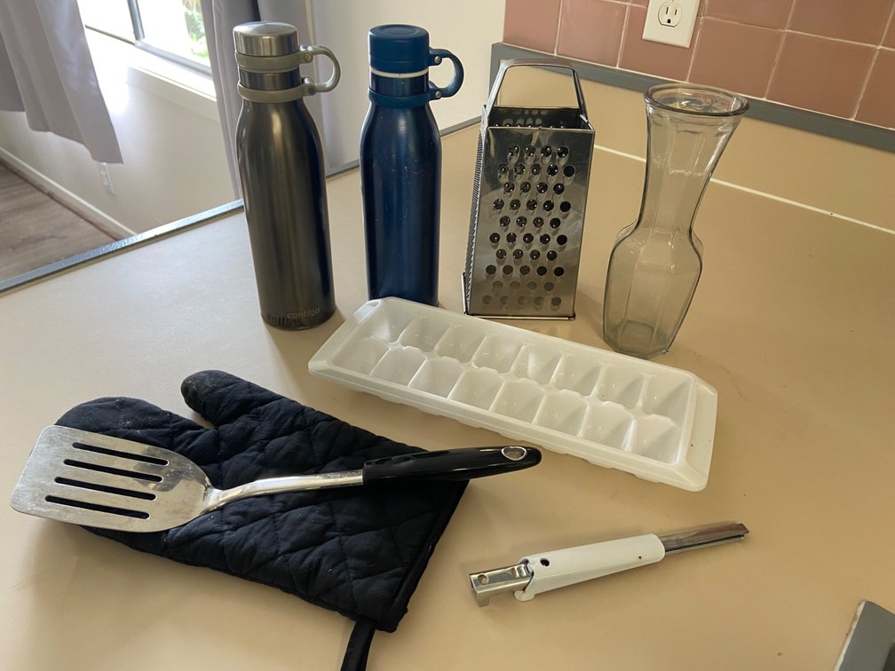Assortment of kitchen items, spatula water, bottles, ice cube tray, jar, opener, vase