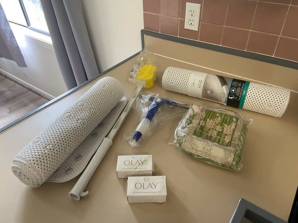 Assortment of bathroom, items, shower curtain window, squeegee with spray, bottle attached