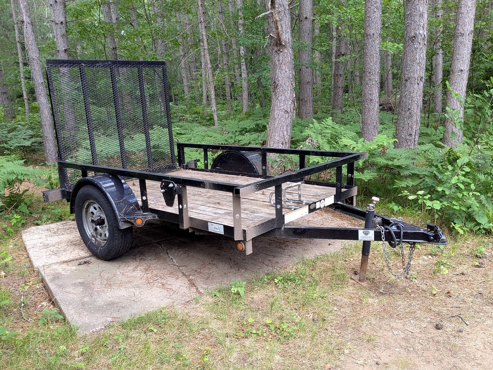 Trailerman 2990 lb GVWR utility trailer has a 5' x 8' deck in good condition, a 4' ramp, motorcycle