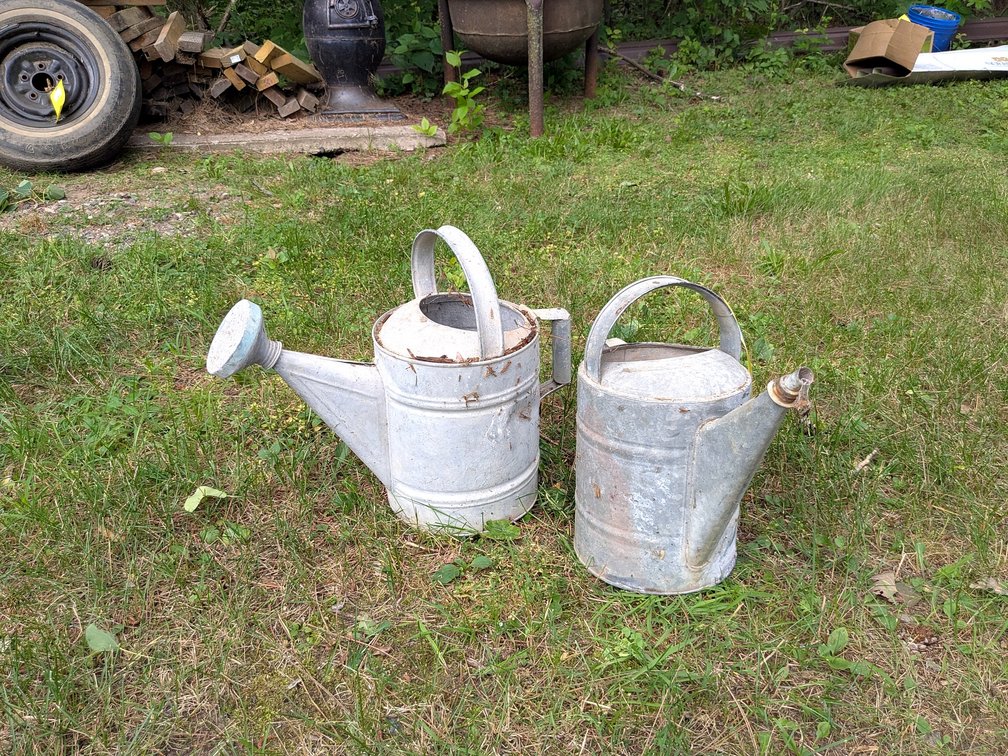Two galvanized watering cans up to approx 15" tall over handle.