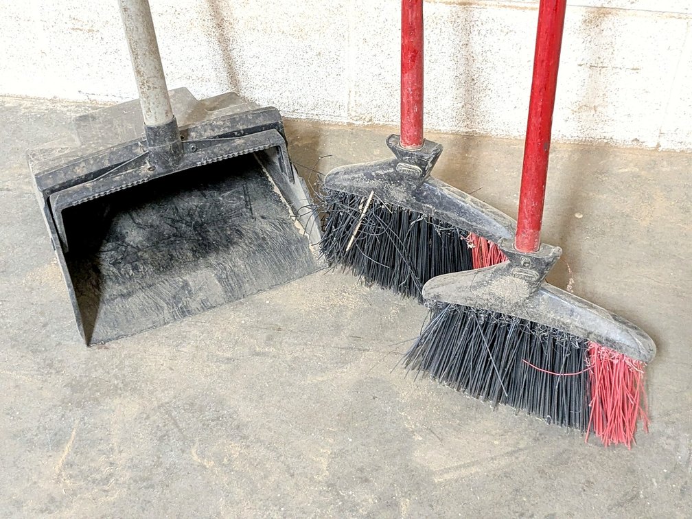 Two shop brooms and a dust pan.