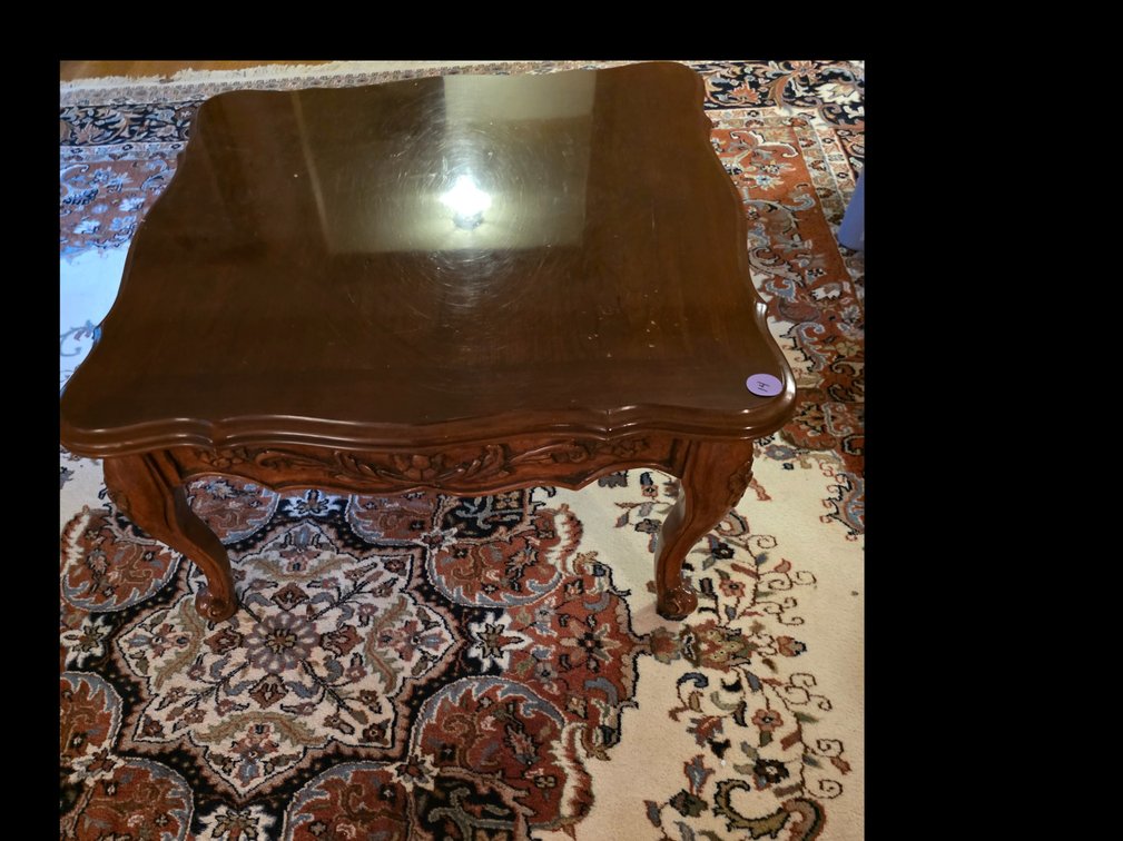 French-style carved wood accent table featuring ornate floral and scroll details along the apron and cabriole legs