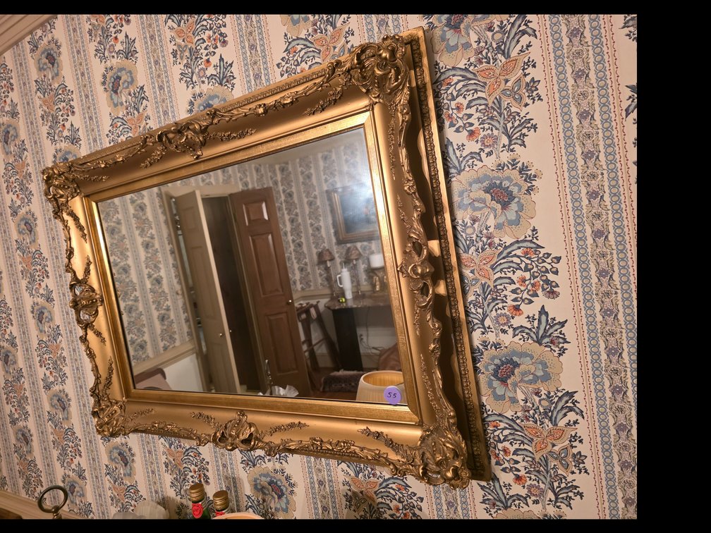 Ornate, French-style gold-gilded wall mirror featuring elaborate scrolling floral carvings