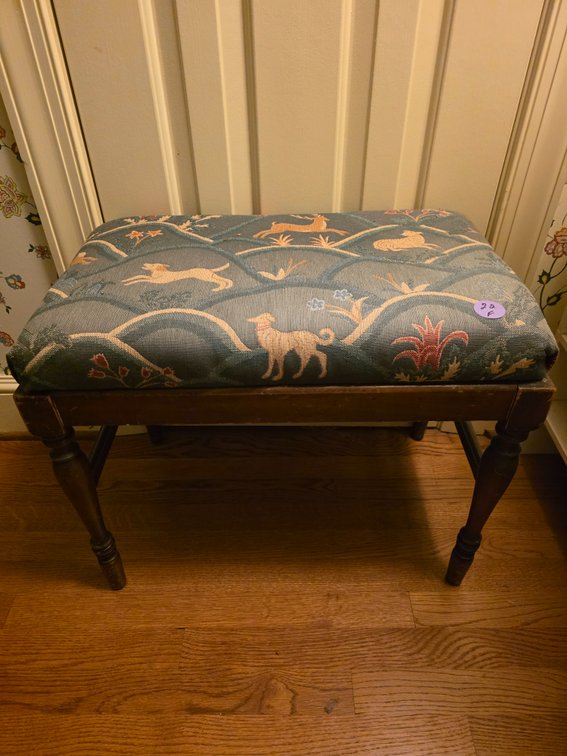 wooden footstool featuring an upholstered blue tapestry top with a distinctive animal and floral motif.