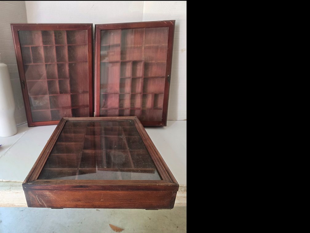 Wooden shadow box or trinket display  featuring multiple small compartments and a glass front door.Key FeaturesMaterial: Brown wood frame with a warm, aged finish.Design: Multi-grid pigeonhole layout design