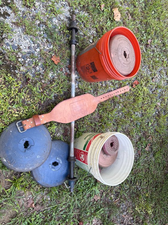 Home gym equipment, cement-filled plastic weight plates, a barbell bar, and a weightlifting belt