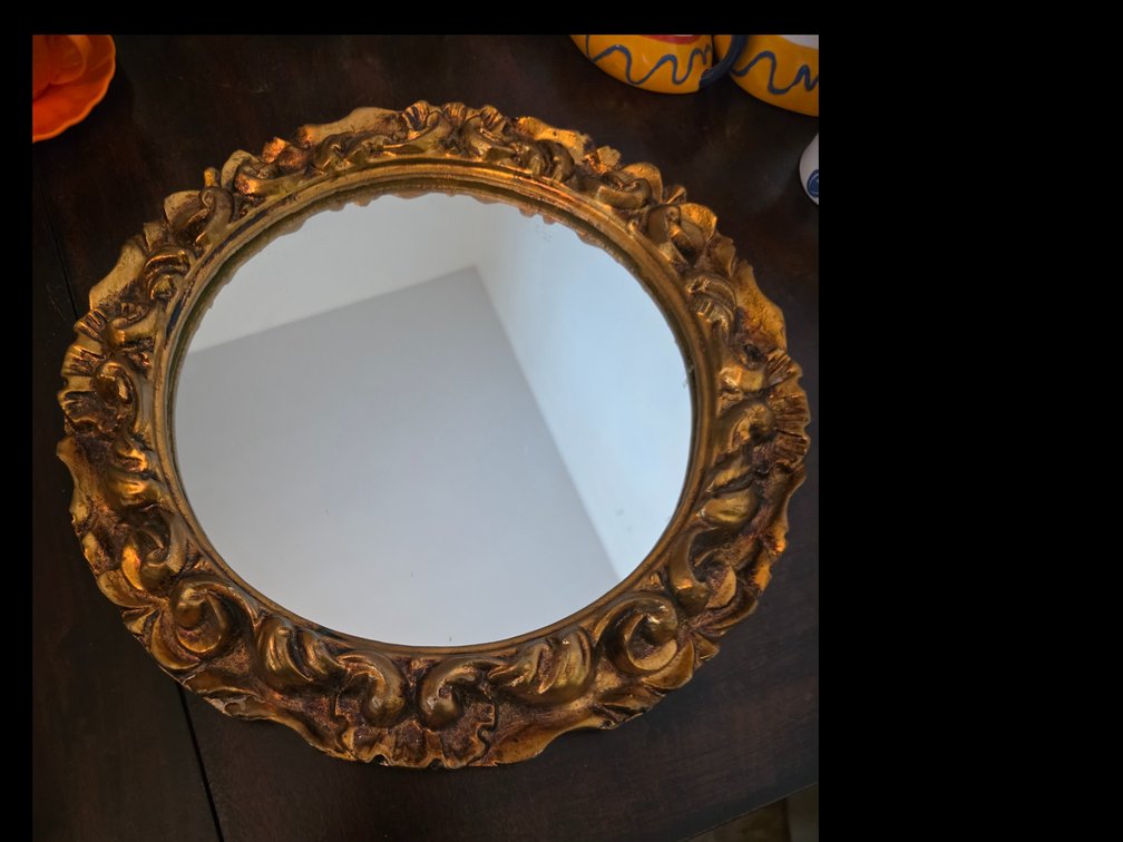 round vintage wall mirror features an ornate, carved gold-gilt frame with classic rococo scrollwork