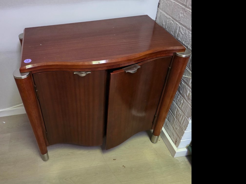 Rivers Edge Art Deco-style wooden cabinet, highlighted by its distinctive serpentine-curved double doors and sleek metallic corner accents.