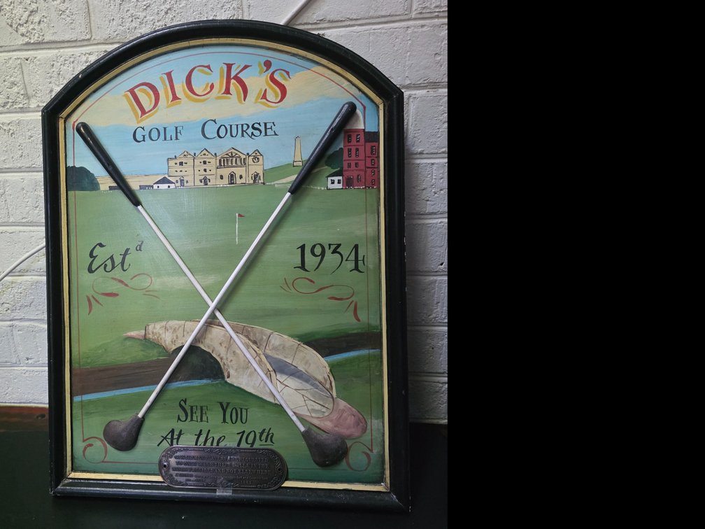Vintage-style decorative wooden wall plaque featuring a hand-painted golf course design labeled "Dick's Golf Course Estd 1934" with two crossed golf clubs mounted on the front.