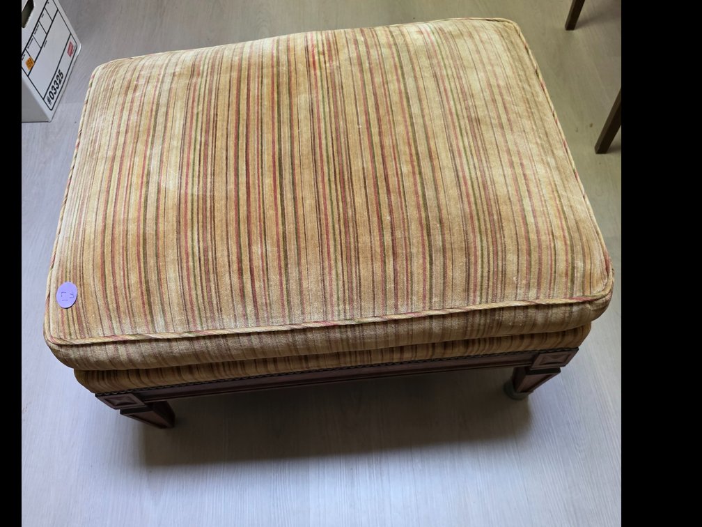 Upolstered ottoman features a warm striped woven fabric and classic wooden legs with detailed carved corner blocks.