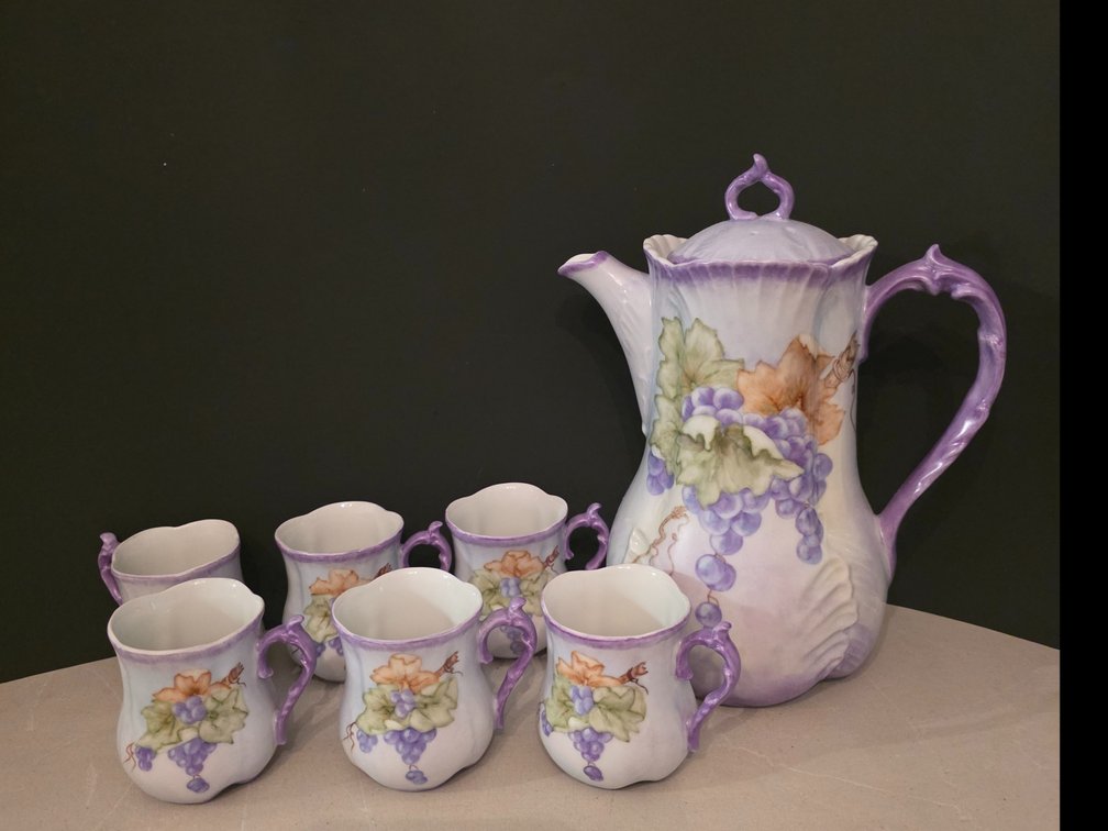 Hand-painted porcelain chocolate pot and matching small cups featuring a delicate purple grape and green leaf motif with lavender accents.