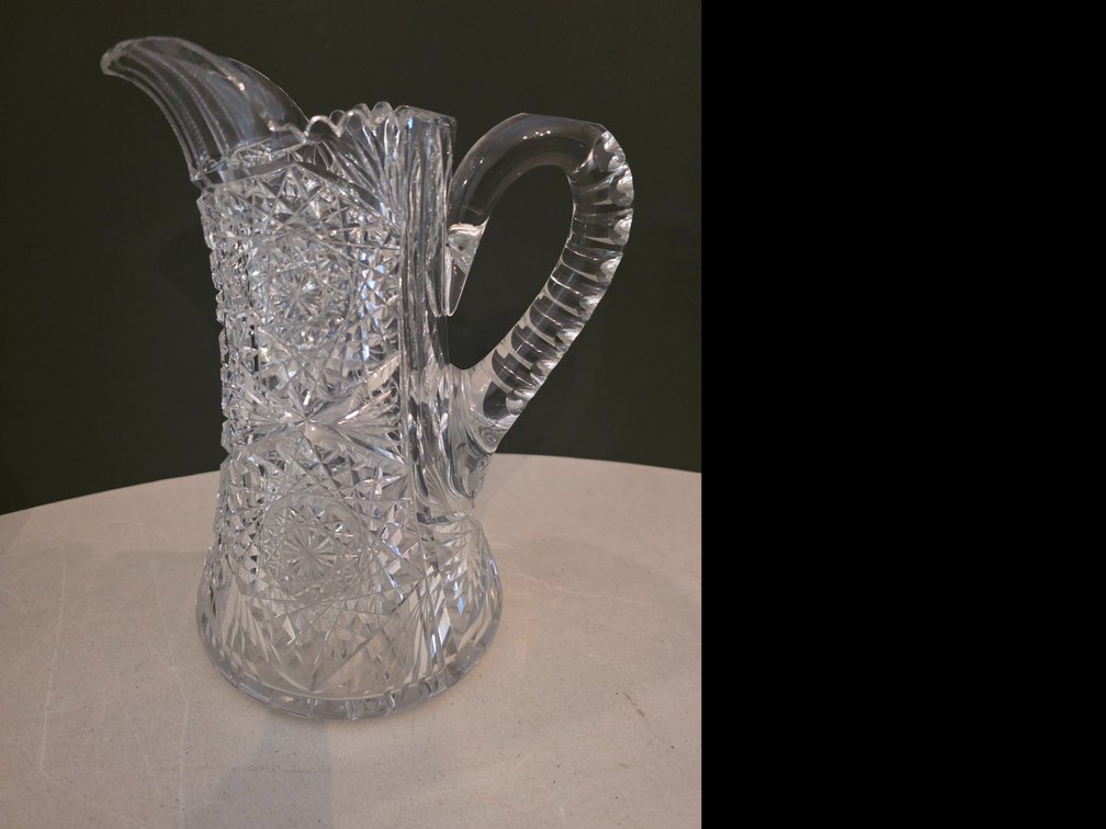 American Brilliant Period cut glass pitcher, featuring a clear lead-crystal body adorned with deeply cut geometric motifs like hobstars,