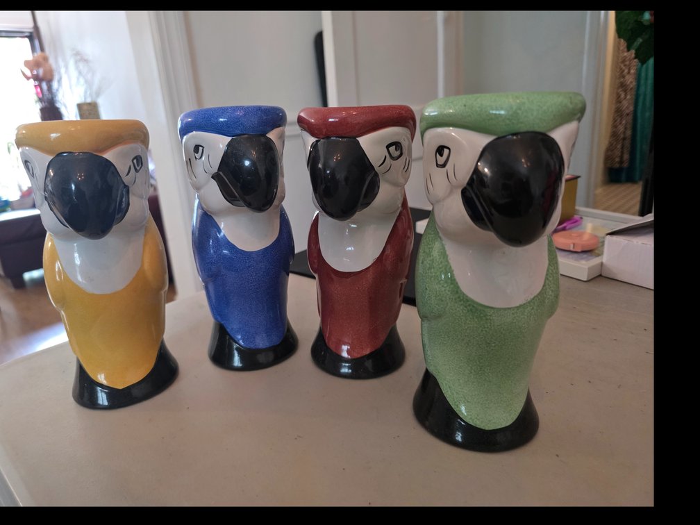 Colorful  parrot tiki mugs feature a vibrant glazed finish and a distinctive black beak design.