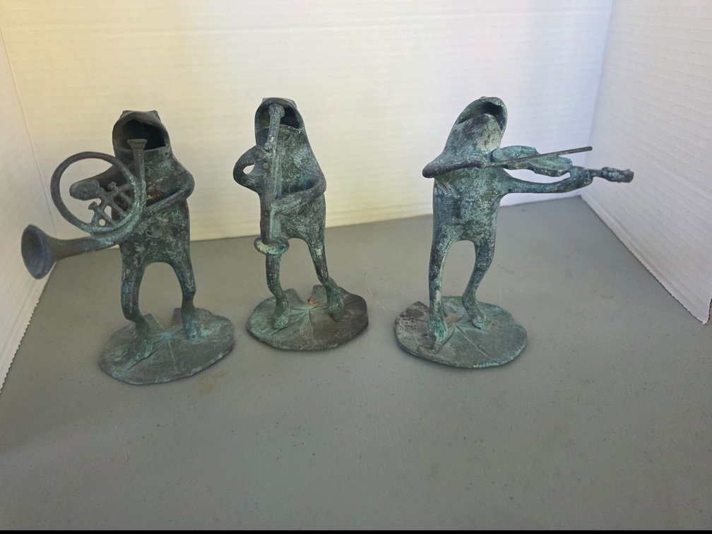 Set of three standing green verdigris patinated metal  frog musician figurines, each mounted on a lily-pad-shaped base, with the figures   playing musical instruments