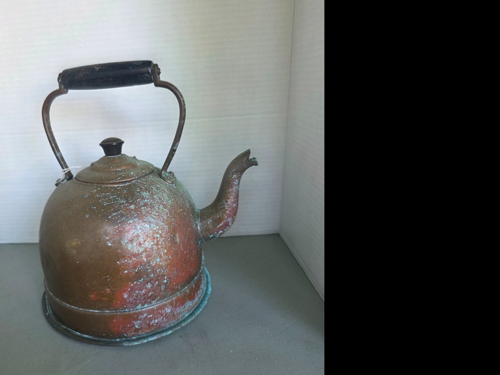 Vintage copper tea kettle with a brass or metal handle featuring a dark wooden grip and a noticeable green-blue patina