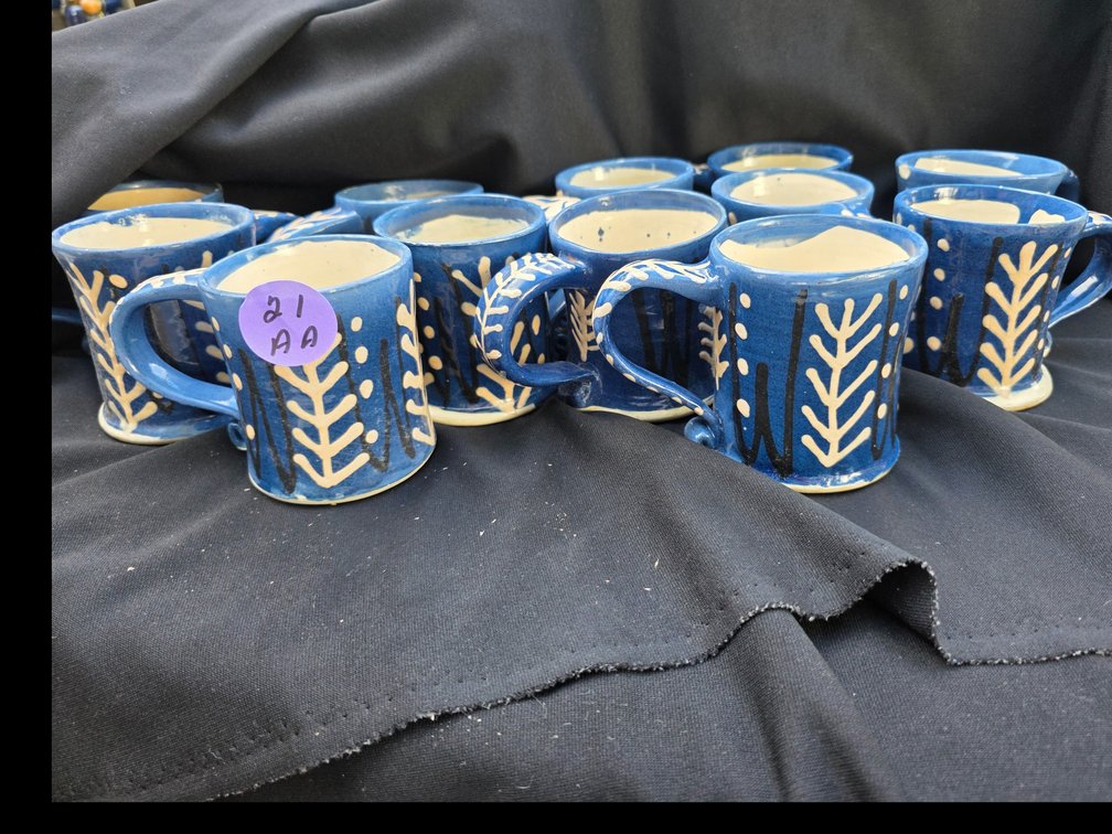 Handmade  coffee mug with a blue glaze and a white-and-black tree or leaf sgraffito pattern.