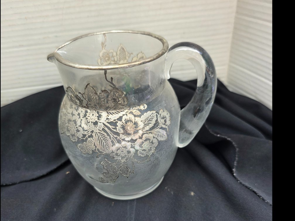 Round glass pitcher featuring a sterling silver floral overlay