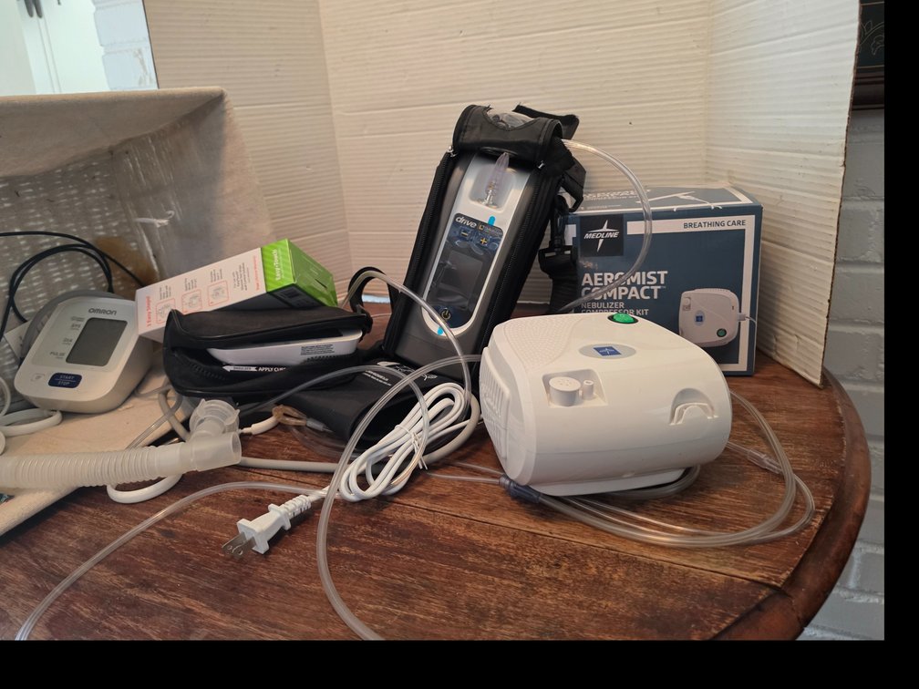 Medical devices,  Aeromist  Compact Nebilizer, Drive DeVilbiss iGo2 Portable Oxygen Concentrator secured inside a black protective carrying case with an oxygen connector nozzle visible at the top. ; Easy Touch Clucose Monitoring  System, etc