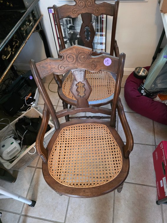 Victorian or Eastlake-style wooden armchair featuring a woven cane seat and scroll armrests.