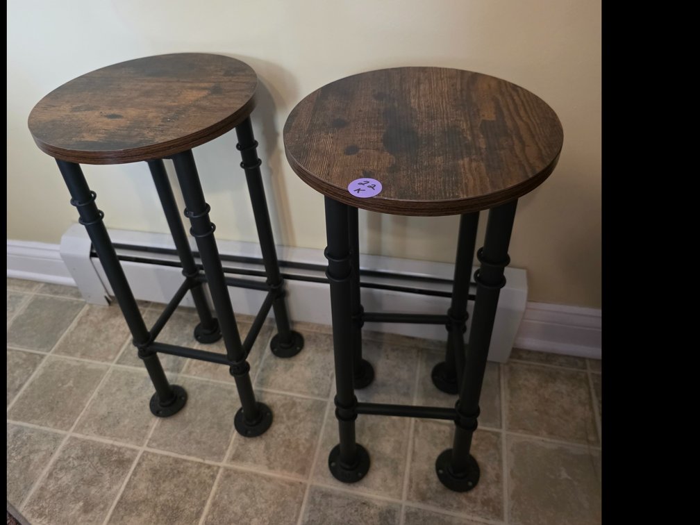 Industrial-style round bar stools with a rustic wood-grain top and black metal pipe-style legs
