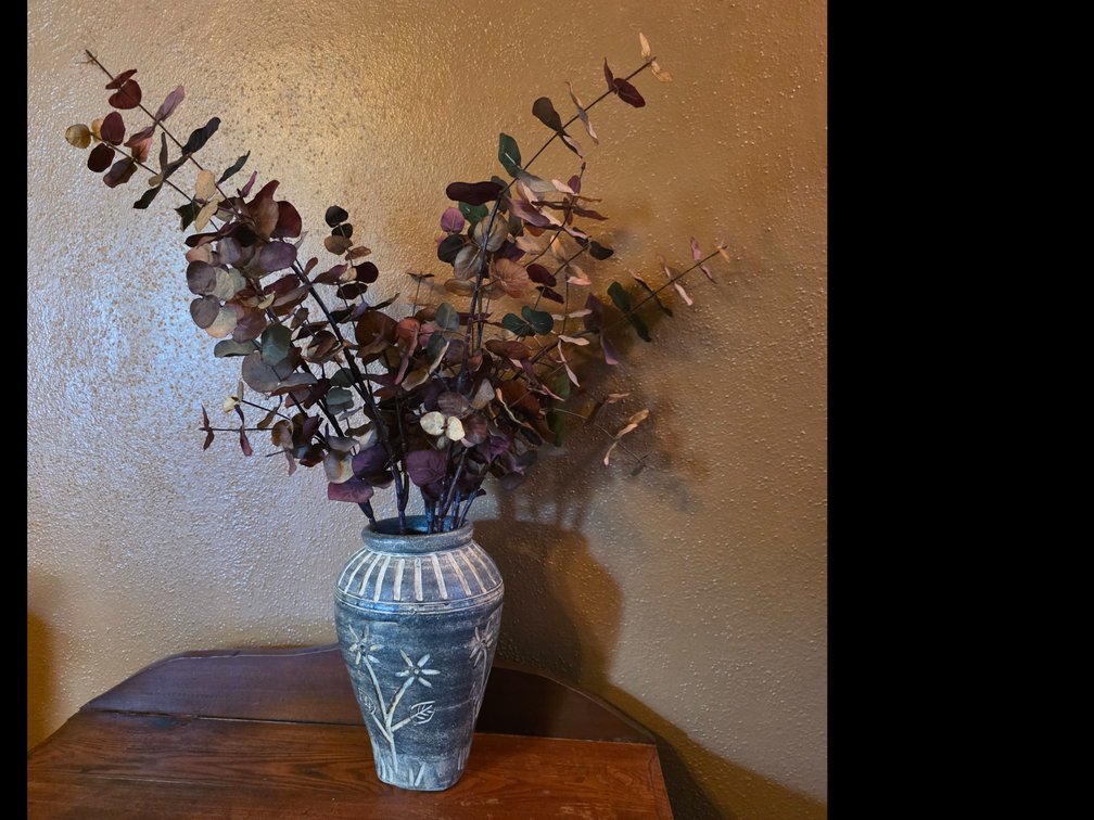 Decorative vase with a rustic dark gray-blue finish, a fluted collar with white-painted vertical stripes, and carved white floral and leaf motifs
