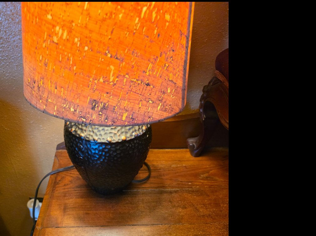 Decorative table lamp featuring a dark, hammered bulbous base