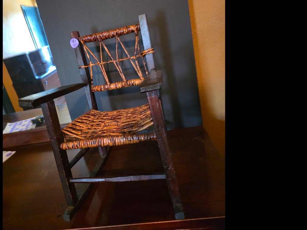 Child's rocking chair in the rustic, featuring a dark wood or bentwood-style frame