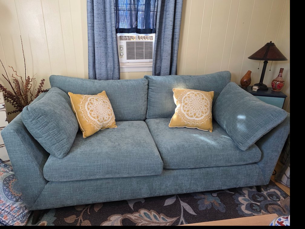 Blue fabric sofa features loose back cushions, wide track or flared arms,