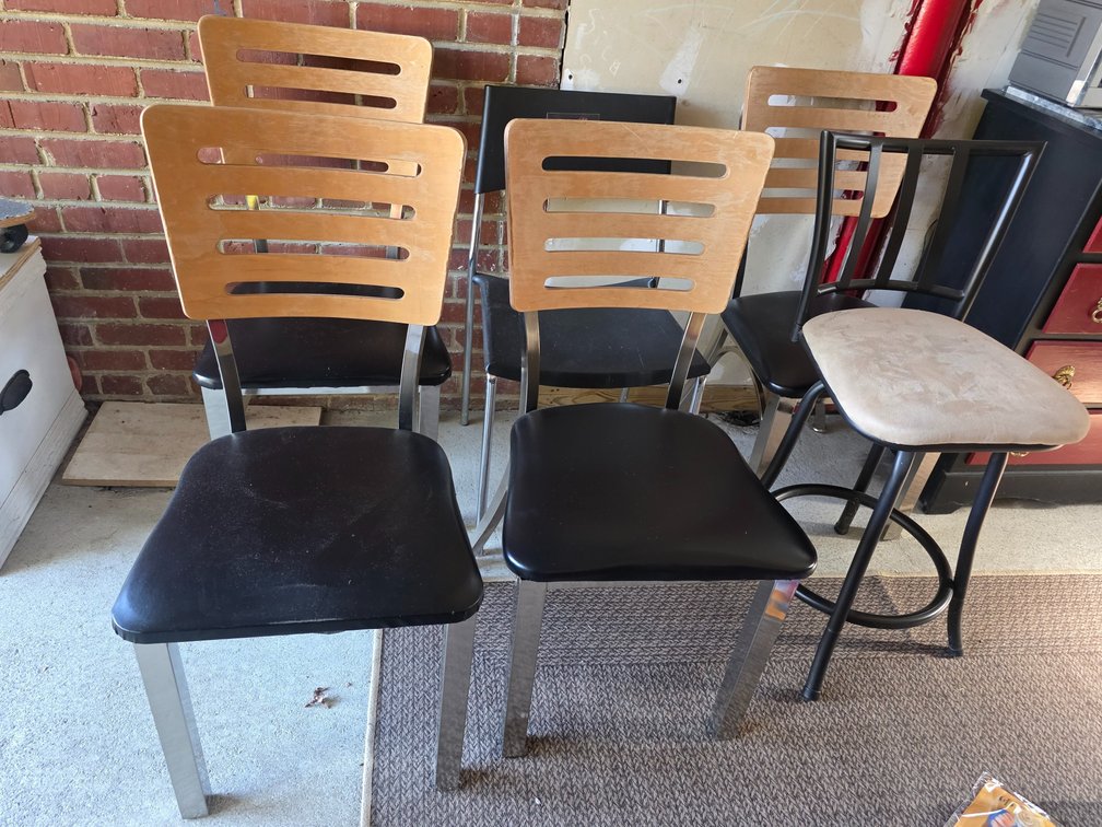 Metal restaurant dining chair featuring a multi-slat wooden backrest and a black padded vinyl seat with a metal frame