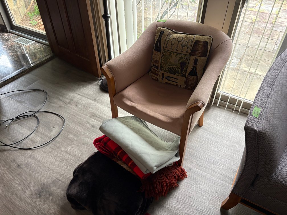 Beige Upholstered Armchair with Decorative Pillow and Assorted Linens