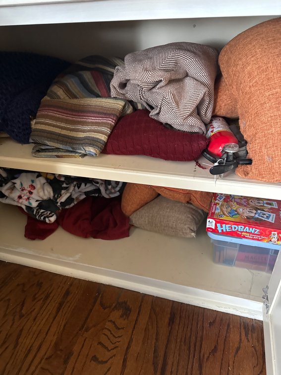 Shelf Contents Including Board Game, Textiles, and Fire Extinguisher