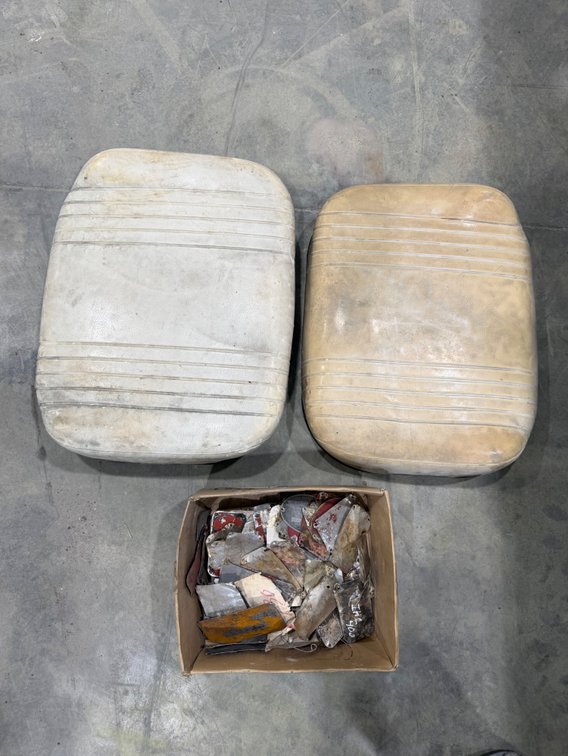 Box of old tractor and implement serial number plates and 2 International 06/56 series bottom seat cushions