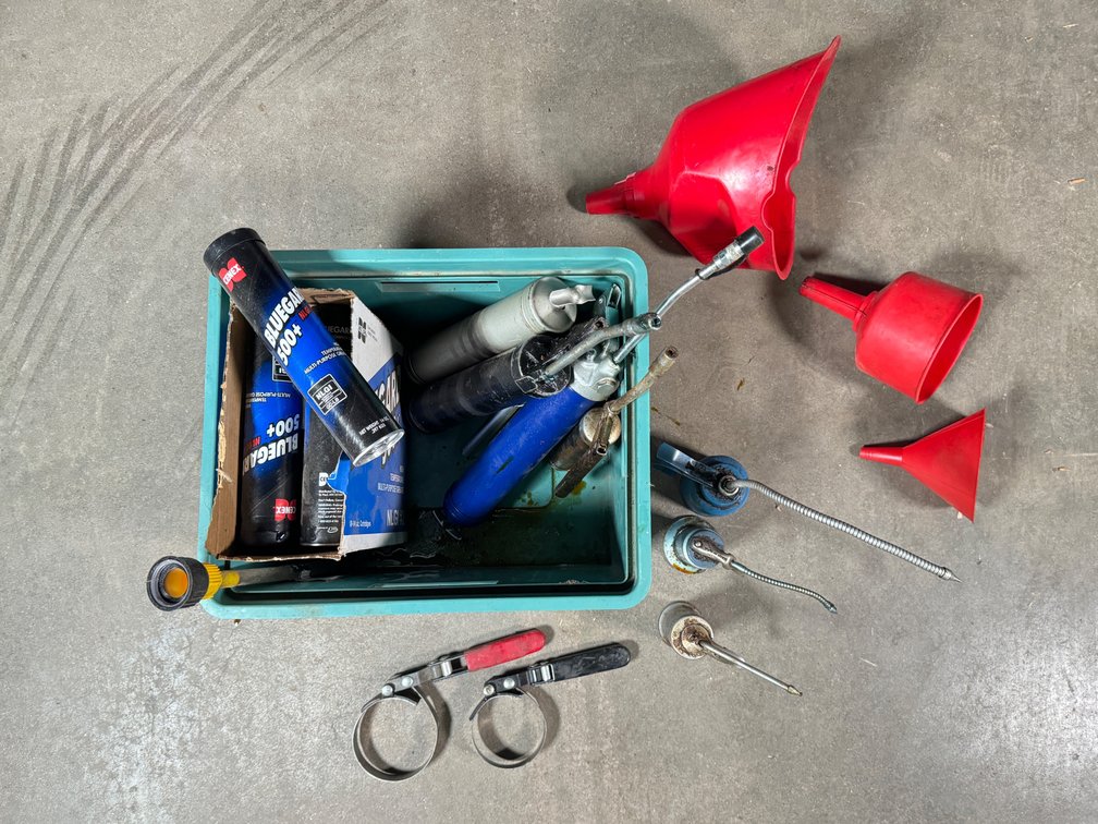Lot of automotive garage greasing tools and unused grease. 